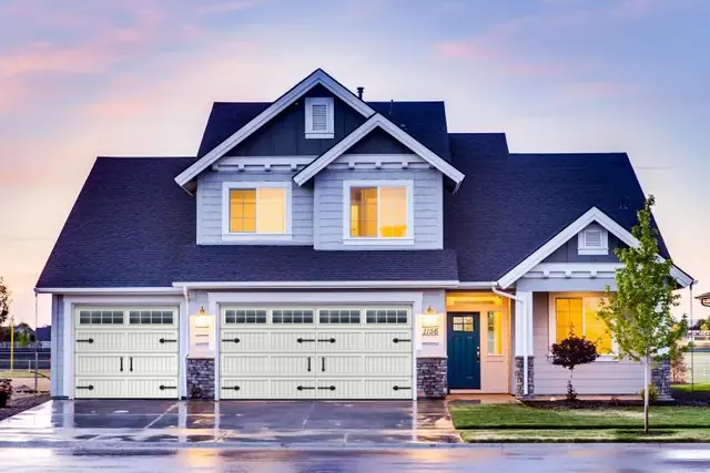 Two-story home with white carriage garage doors, rendered in our door visualizer